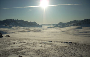 飛行機雲と太陽が雪原の上に重なり合う